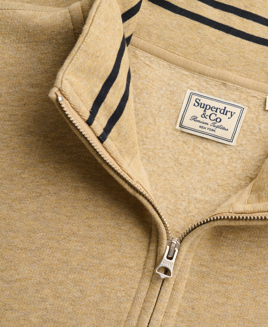 Superdry & Co woven label on tan half-zip knit top with zip pull