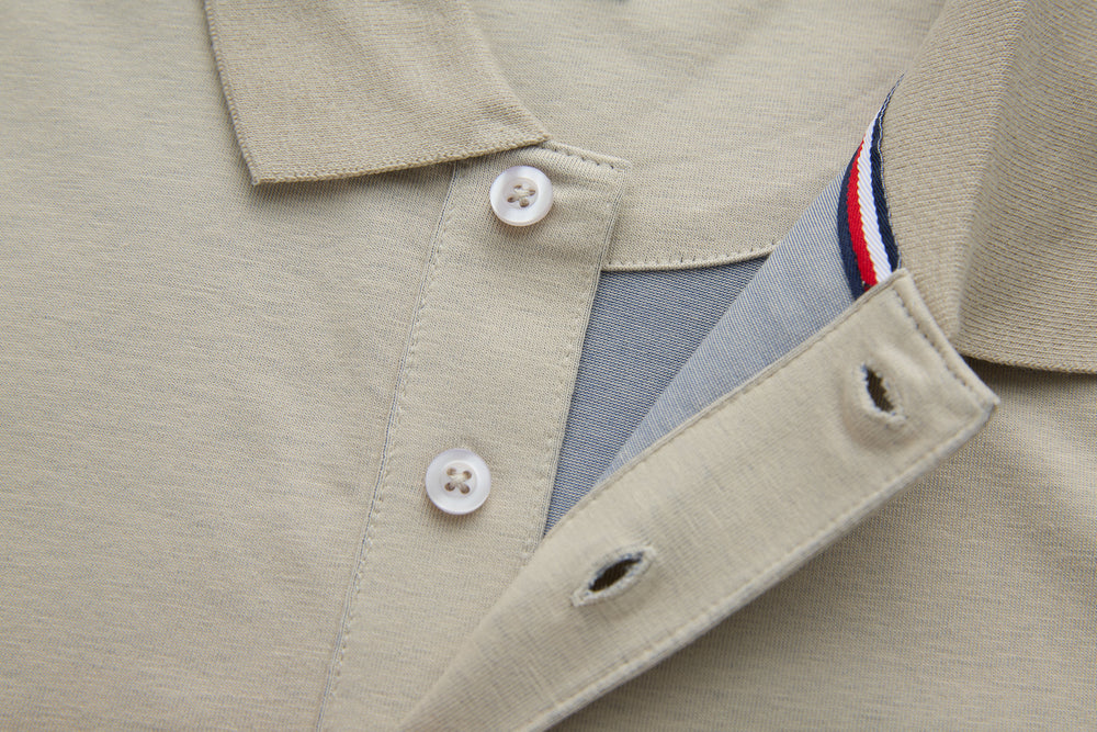 Beige polo shirt with collar, white buttons, and partial striped inner trim