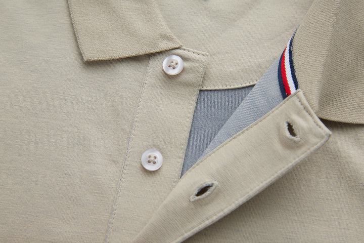 Beige polo shirt with collar, white buttons, and partial striped inner trim