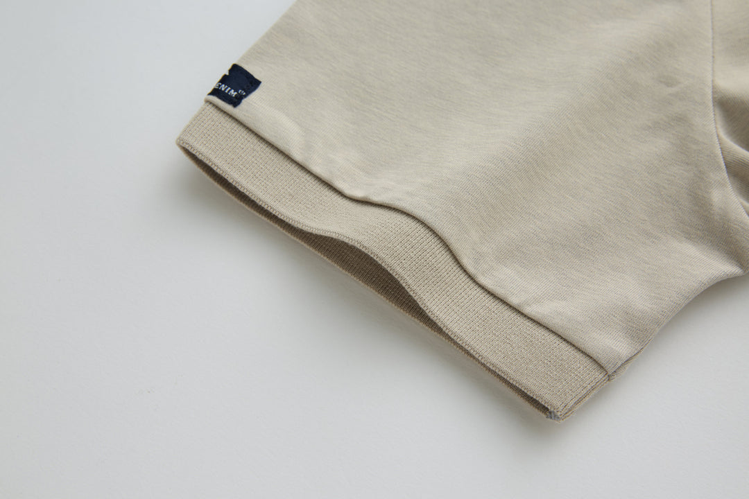 Beige polo shirt sleeve cuff with small woven brand tag