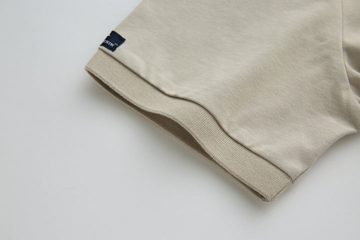 Beige polo shirt sleeve cuff with small woven brand tag