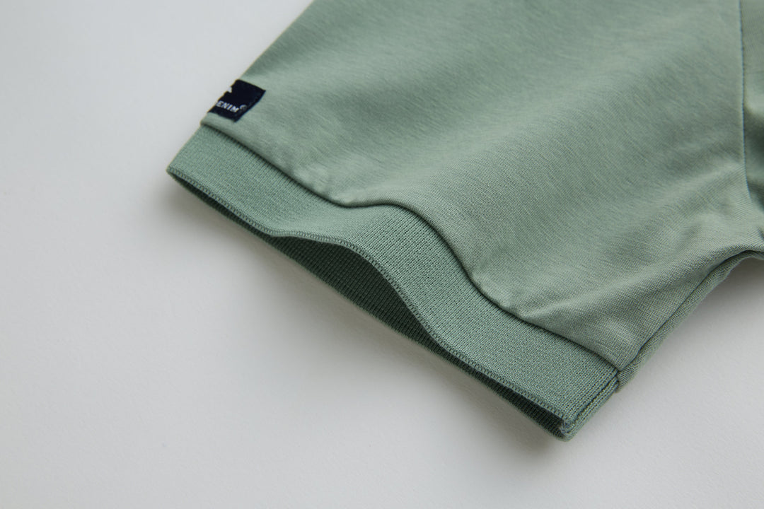 Mint polo shirt sleeve cuff with small branded tag at hem