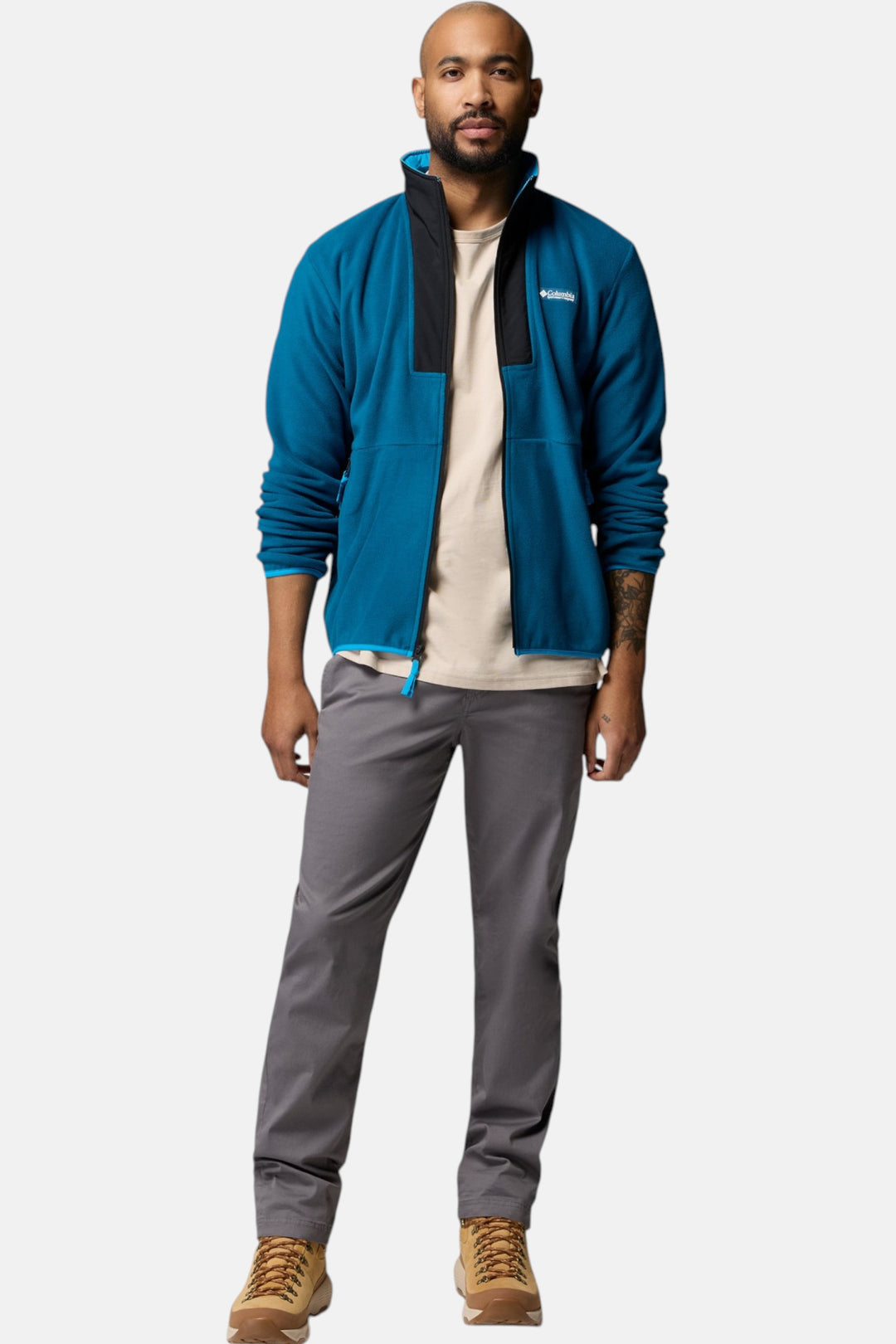 Men's blue full-zip fleece jacket with stand collar and zip pockets, styled with gray pants