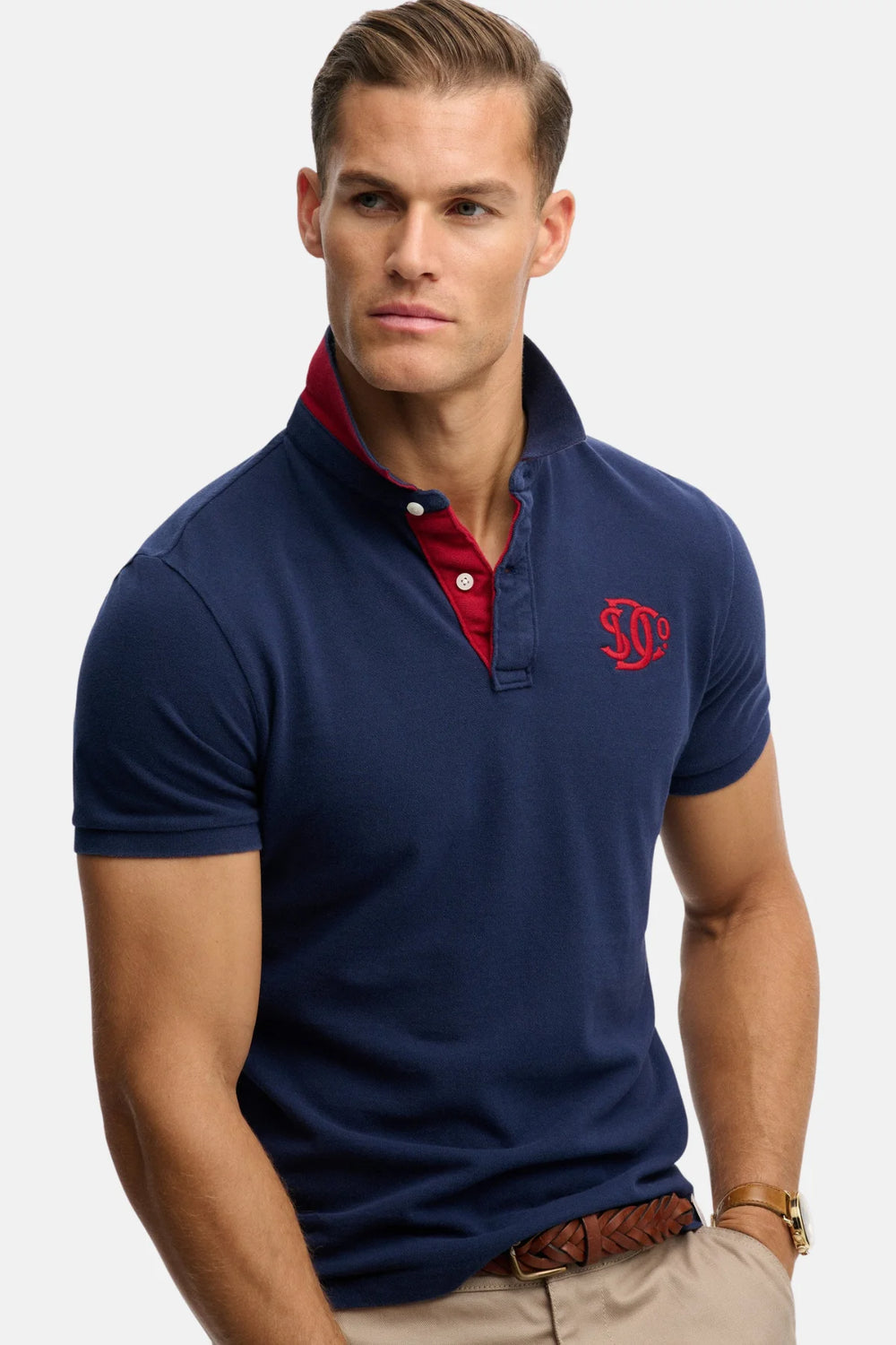 Dark navy polo shirt with red collar and red monogram on left chest, short sleeves